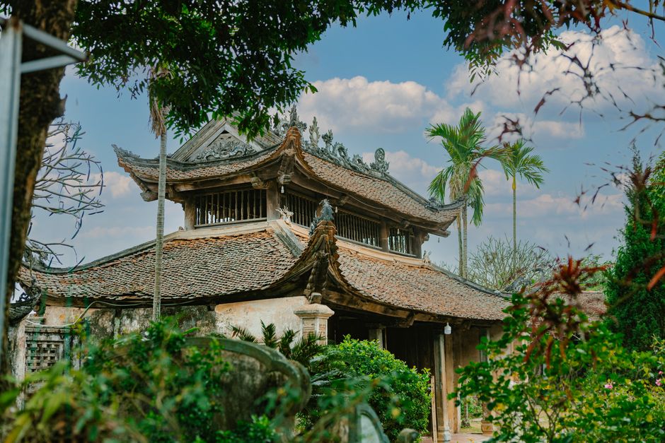 A beautiful traditional Asian temple surrounded by lush greenery under a clear blue sky.
