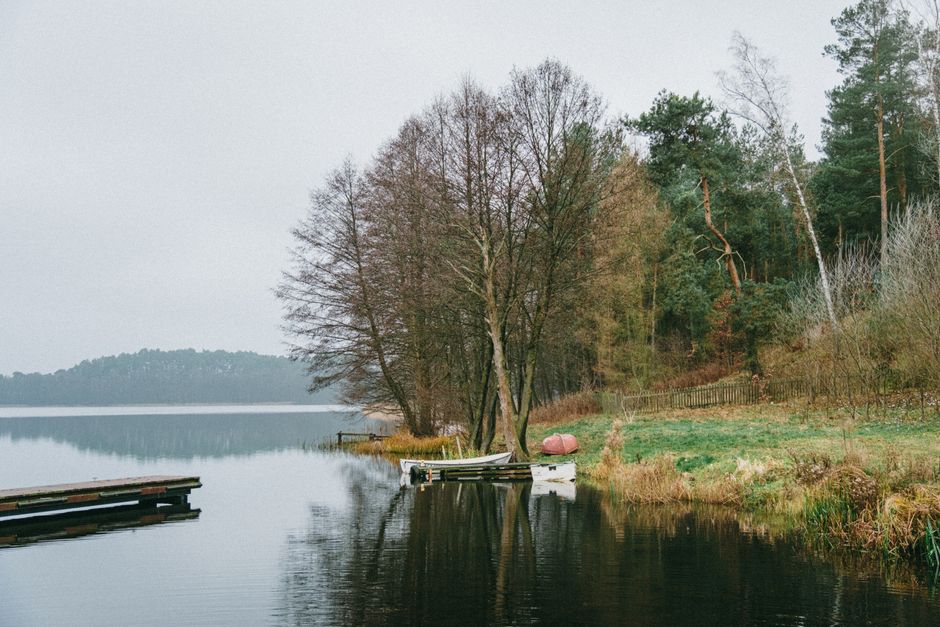 A serene lakeside scene in Poland featuring boats, trees, and a tranquil atmosphere.