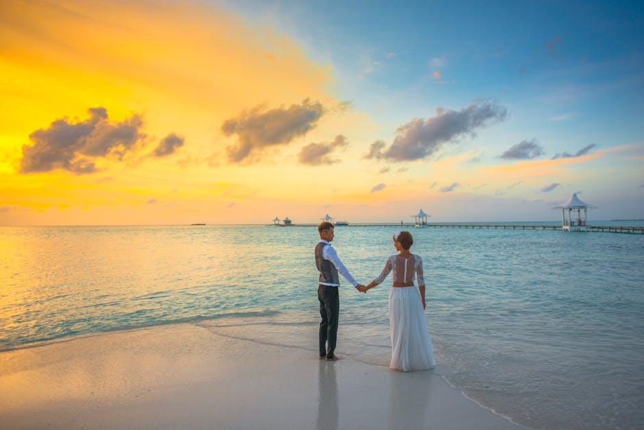 A romantic couple holding hands at sunset on a Maldives beach, exuding love and tranquility.