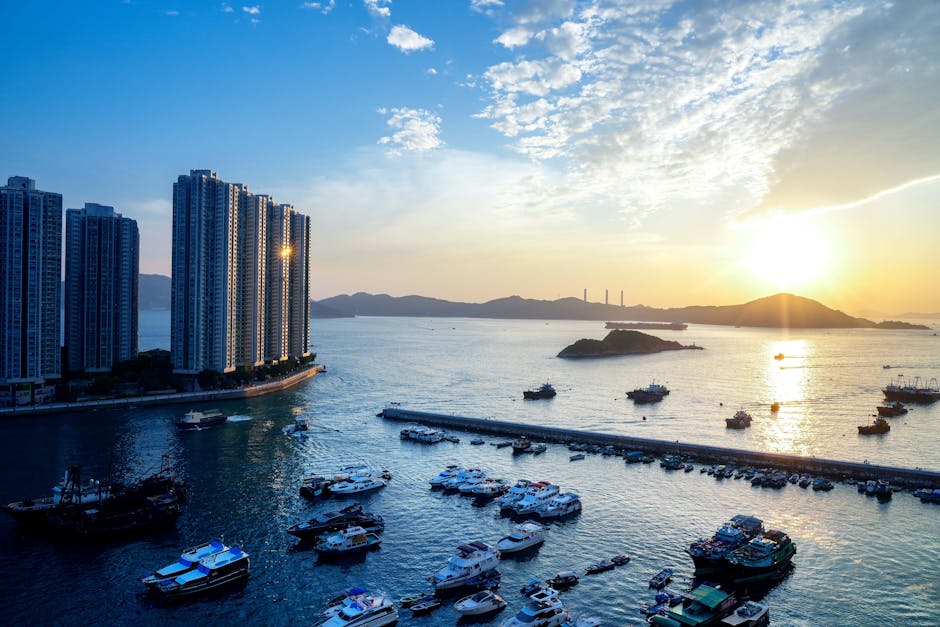 Explore the breathtaking view of Hong Kong's skyline and harbor at sunset with boats and islands.