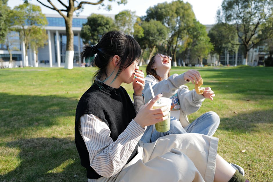 Asian women enjoying a picnic with drinks and snacks on a sunny campus lawn, depicting happiness and leisure.