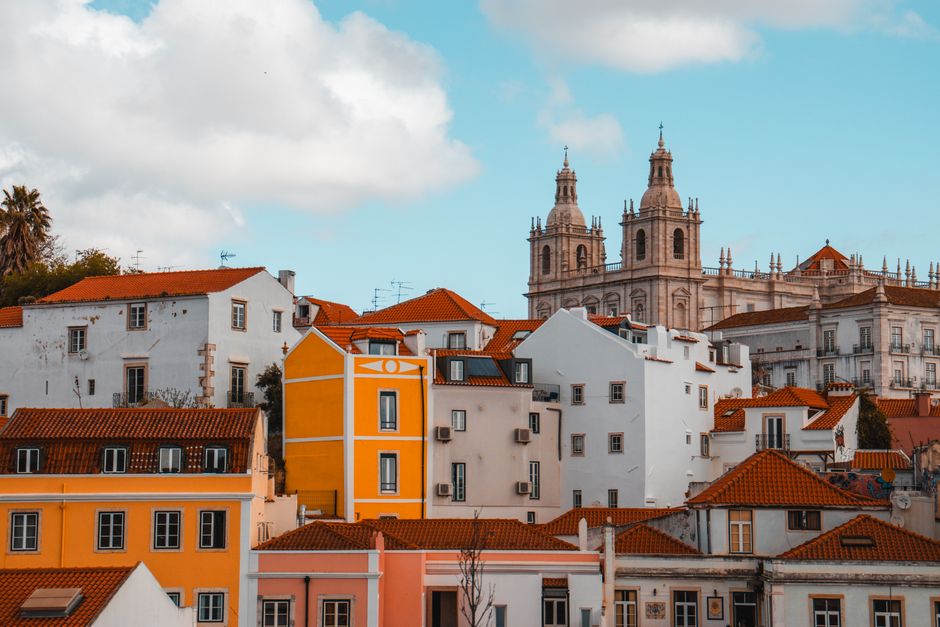 Scenic view of colorful Lisbon rooftops with church towers under blue skies.
