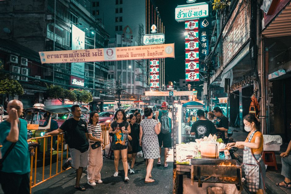 Explore the vibrant street market in an Asian city at night filled with people and neon li