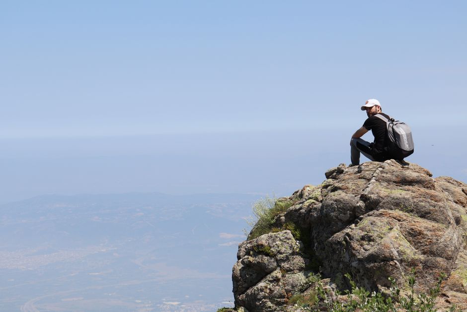 Man sitting on a rock formation enjoying the scenic mountain view in Bursa, Türkiye.