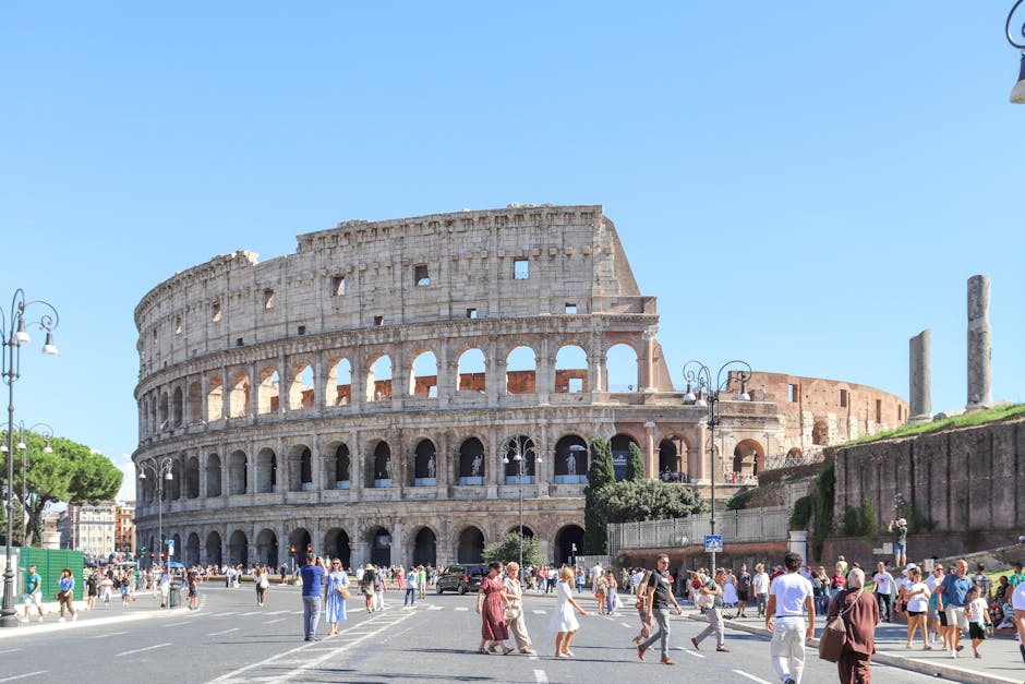 The Colosseum with tourists in Rome on a bright summer day, showcasing its historical grandeur.