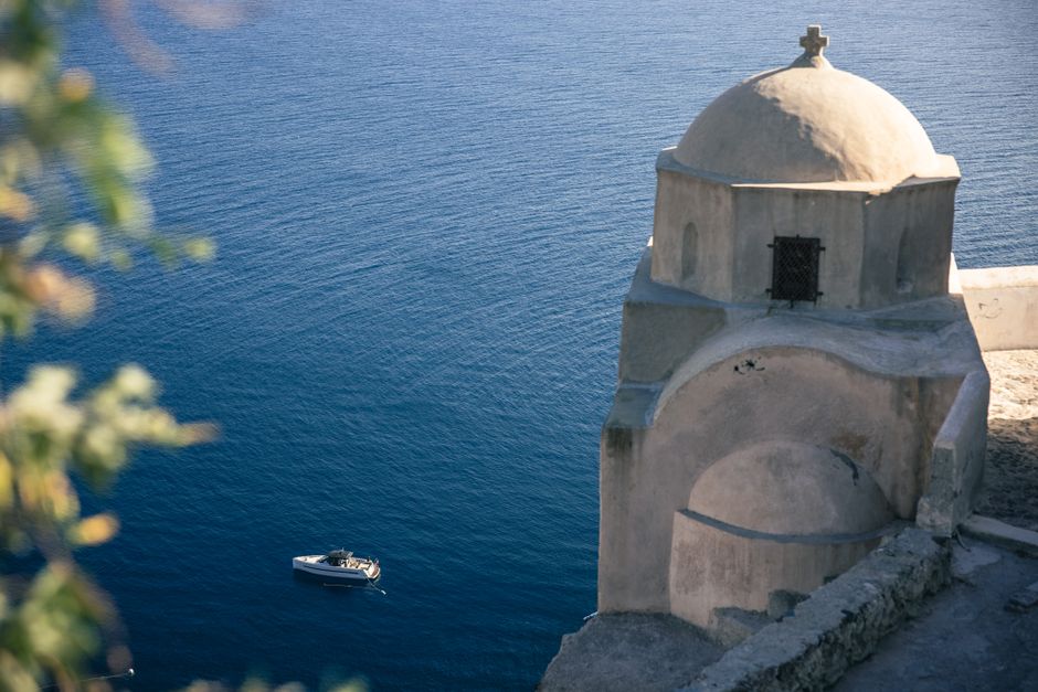 A stunning view of the deep blue Aegean Sea with a traditional church in Santorini.
