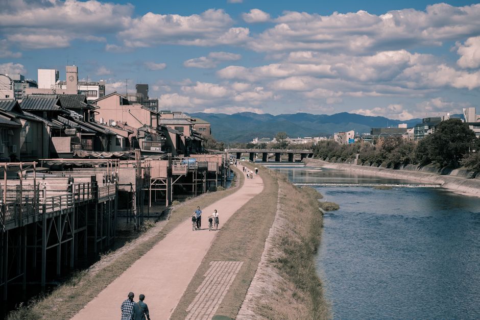 A scenic riverside path in Kyoto, Japan, with people enjoying a leisurely walk.