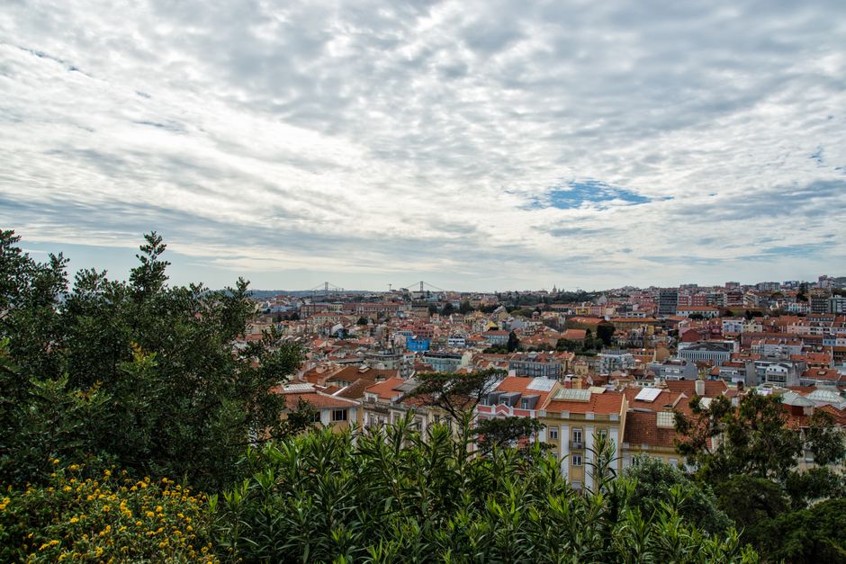 Explore the vibrant rooftops of Lisbon beneath a dramatic cloudscape. Perfect for travel and architecture enthusiasts.