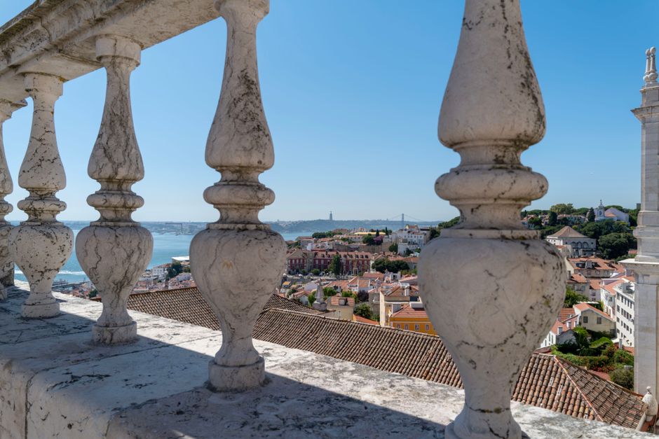 A stunning view of Lisbon's old town and Tagus River seen through a classic stone balustrade.