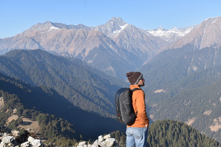 A man with a backpack enjoys a stunning view of the Himalayan mountains.