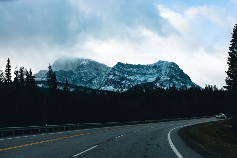 A scenic view of snow-capped mountains along a winding road in Kootenay Crossing, BC, Canada.
