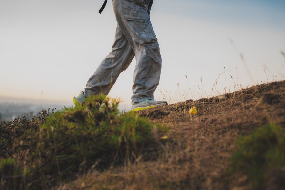 Person hiking on a grassy hillside during dusk in Anantnag, showcasing serene outdoor adve
