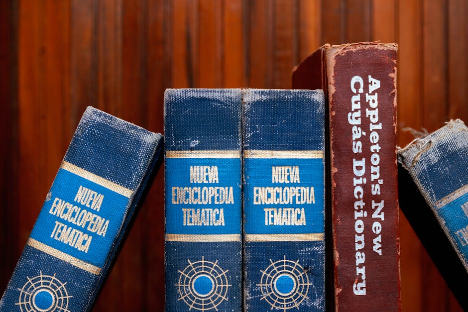 Close-up of old encyclopedias and a dictionary on a wooden shelf, showcasing vintage charm.