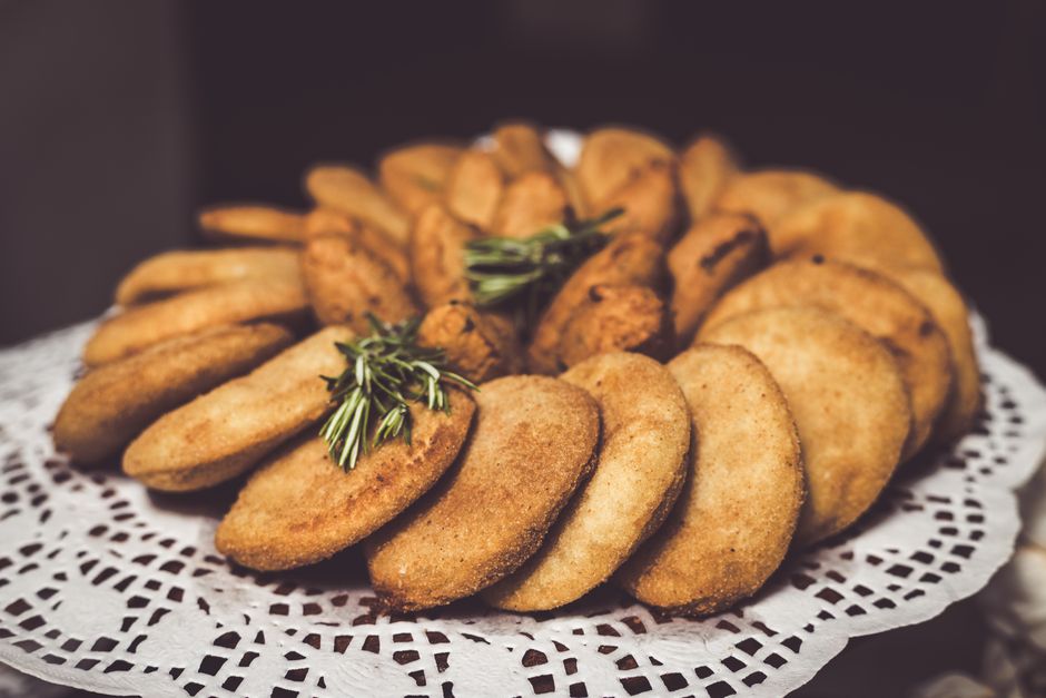 A close-up of traditional Angolan pastries served elegantly on a lacy platter accentuated with green garnish.