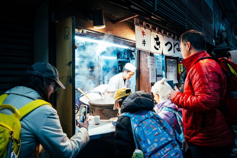 A bustling street food stall in Tokyo, Japan, attracts a crowd at night with delicious offerings.