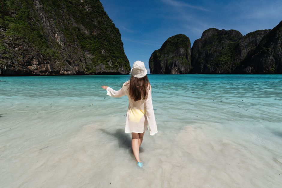 Young woman on a sunny day, strolling in clear waters at Krabi beach, Thailand.