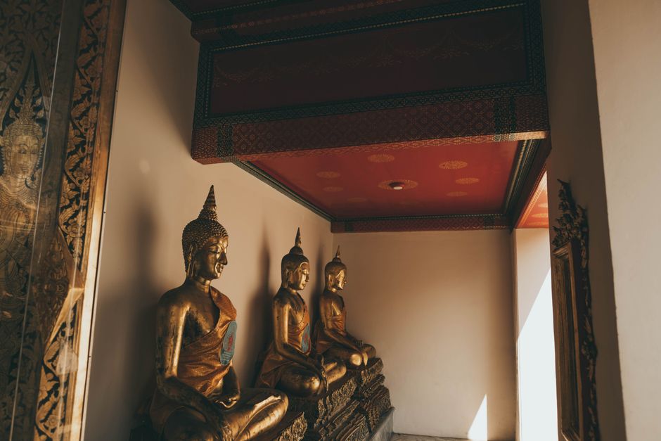 Golden Buddha statues inside a Bangkok temple, showcasing traditional Thai architecture.