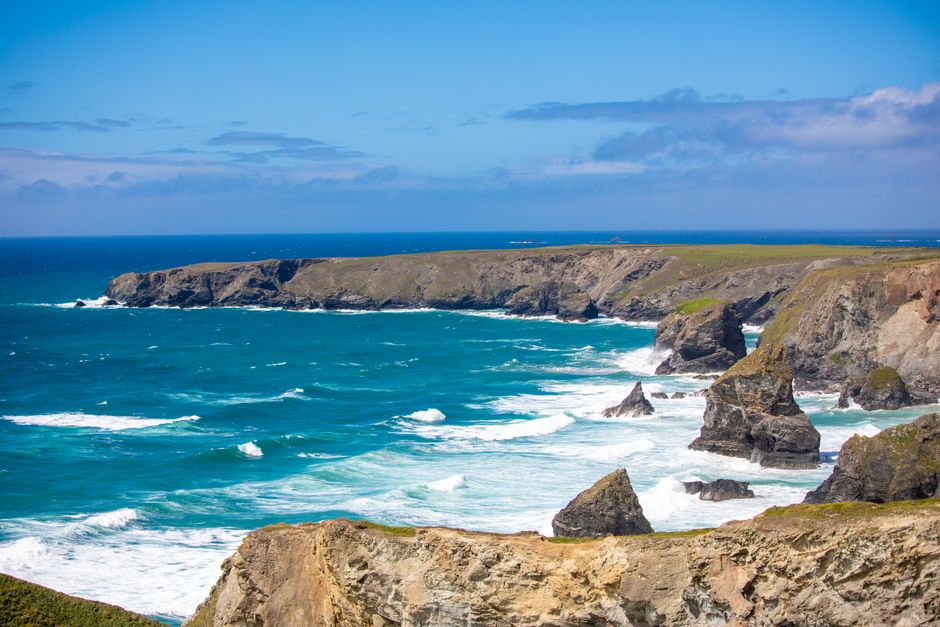 Stunning view of rocky cliffs and crashing waves under a clear blue sky.