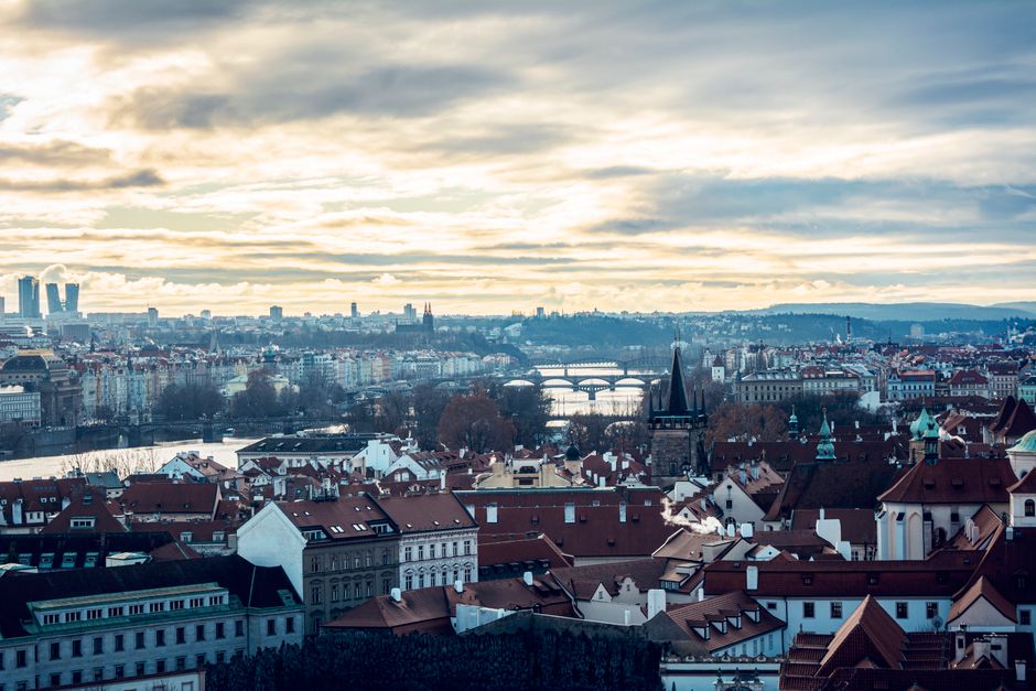 Stunning aerial view of Prague featuring historic architecture and bridges during sunset.