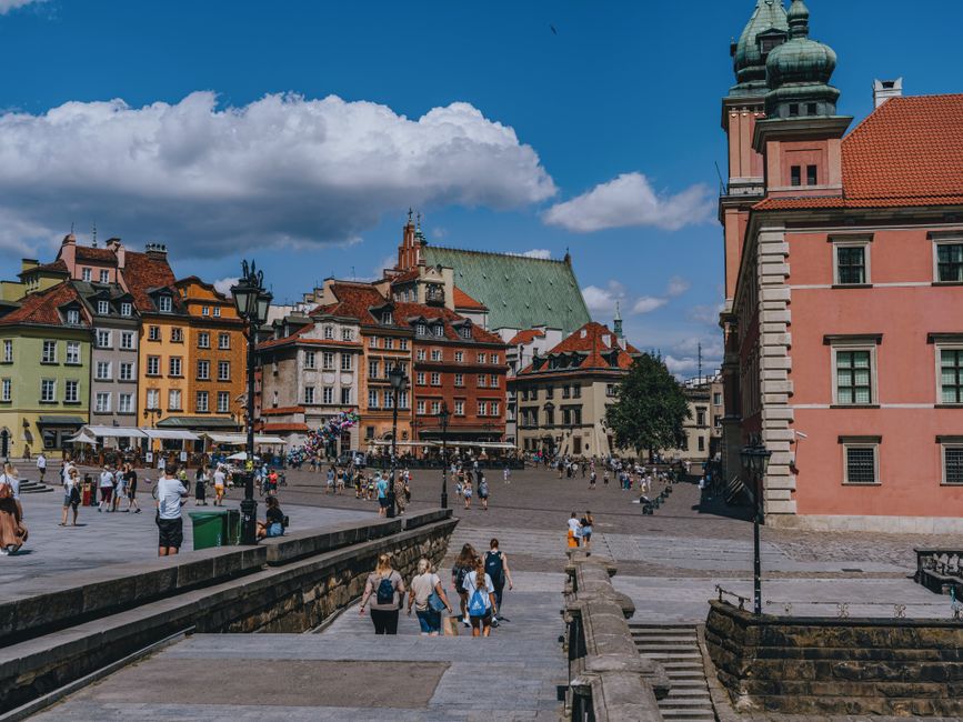 Vibrant scene of Warsaw's Old Town Square with colorful historic buildings and lively atmosphere.