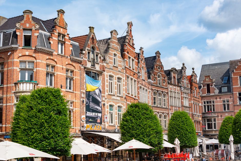 Picturesque view of European street with historic brick buildings and outdoor cafes under blue skies.