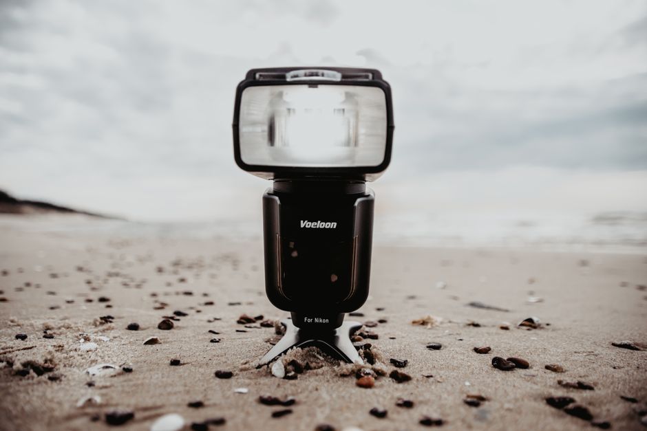 A close-up shot of a camera flash on a sandy beach with a cloudy sky.