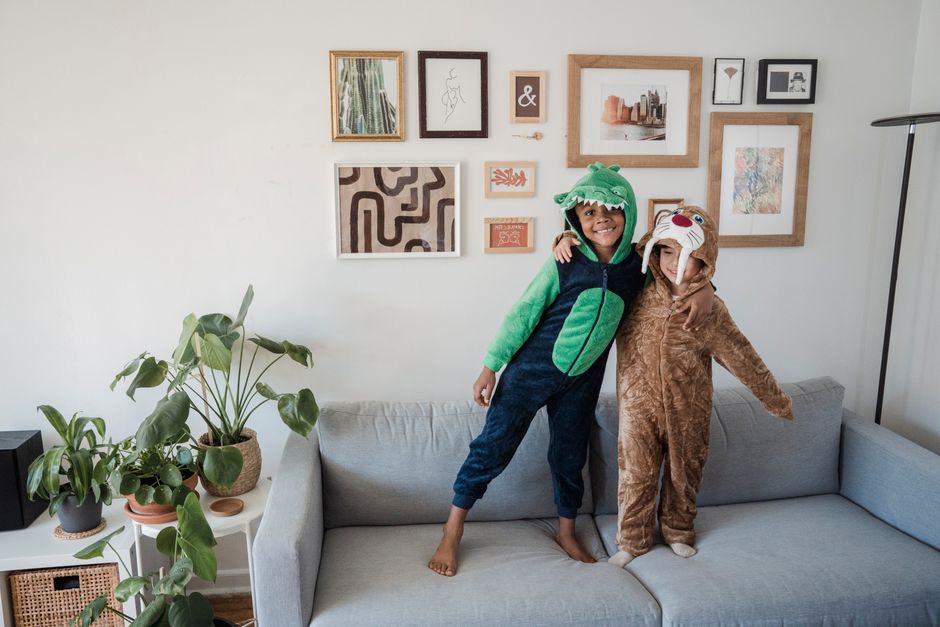 Two kids in animal costumes having fun on a couch in a cozy home setting.