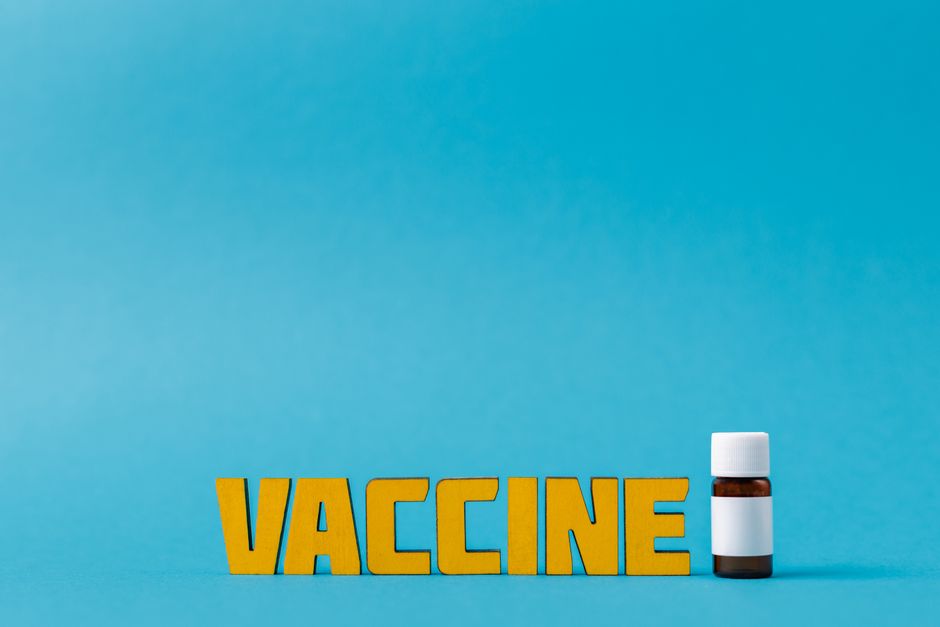Yellow vaccine text with a bottle on a blue background, symbolizing healthcare.