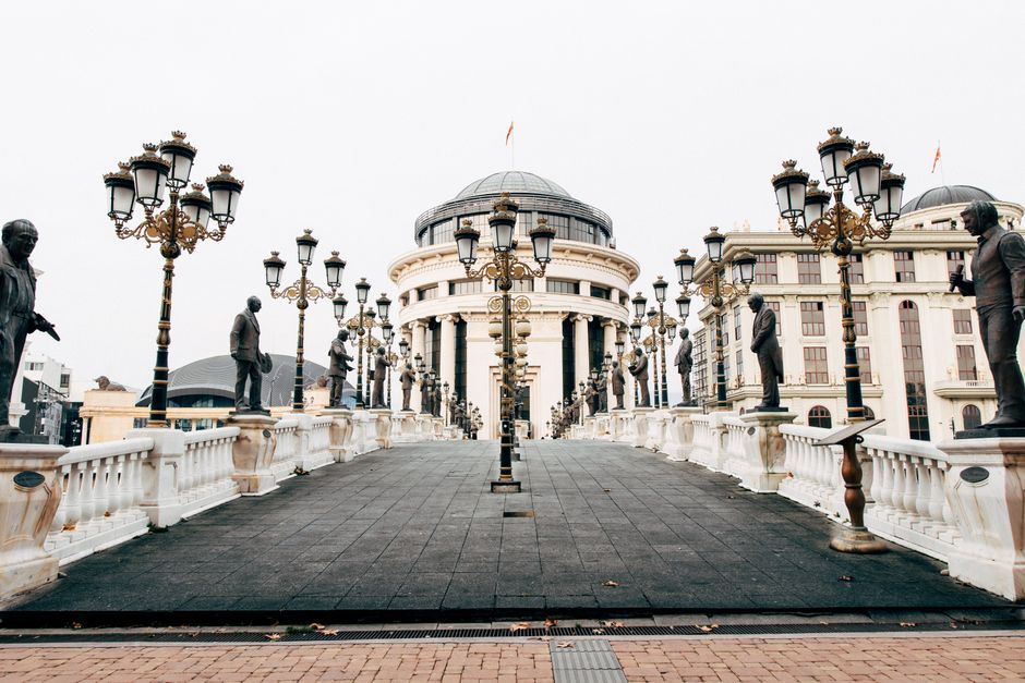Stunning view of an architectural bridge adorned with sculptures, leading to grand buildings in Skopje.