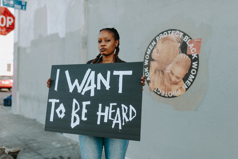 African American woman at protest holding a sign reading 'I Want to Be Heard.'
